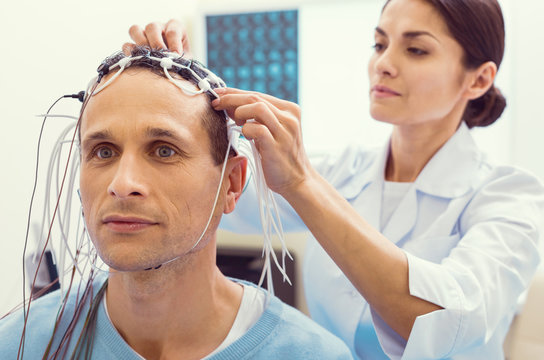 Preparing for analysis. Selective focus on a male patient sitting in a lab and waiting for the notes to be adjusted before undergoing an electroencephalography procedure.
