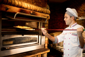 Chef prepares pizza in the oven