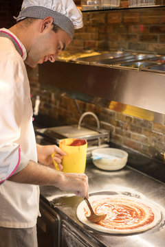 chef baker in white uniform making pizza at kitchen