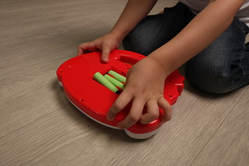 baby inserts batteries into a child's toy. child is dangerous playing with batteries
