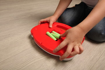 baby inserts batteries into a child's toy. child is dangerous playing with batteries