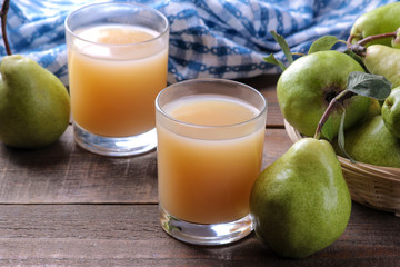 Pear juice and fresh ripe pears on a brown wooden table. close-up