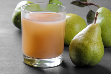 Pear juice in a glass and fresh ripe pears on a black table. close-up