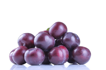 fresh ripe delicious plums stacked in a pile on a white isolated background
