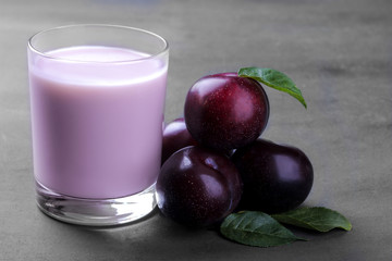 yoghurt from plum and fresh ripe plums with leaves on a gray background. close-up