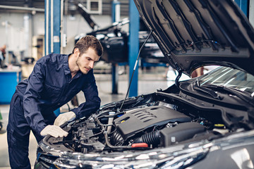 Auto car repair service center. Mechanic examining car engine