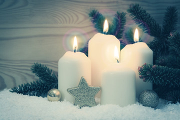 Four burning Advent candles and white snow.