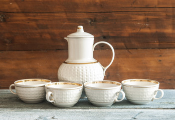 Vintage ceramic set from a teapot, cups  on a wooden table. Copy space