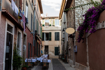 Fototapeta na wymiar cozy narrow street with traditional houses and outdoor cafe in provence, france