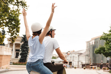Back view of cheerful couple in helmets riding on scooter © Drobot Dean