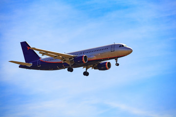 Dark silhouette of a passenger aircraft flying in bright blue sky