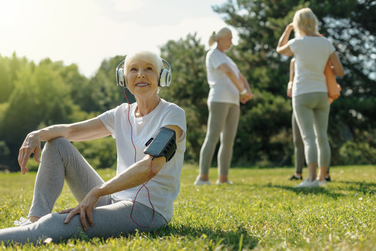 Time to relax. Cheerful retired woman grinning broadly while taking a break after an intensive training session.