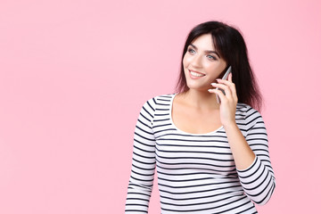 Young woman with smartphone on pink background