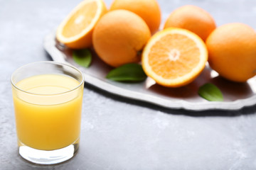Glass of juice with orange fruit on grey wooden table