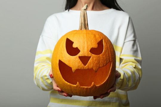 Female hands holding halloween pumpkin on grey background