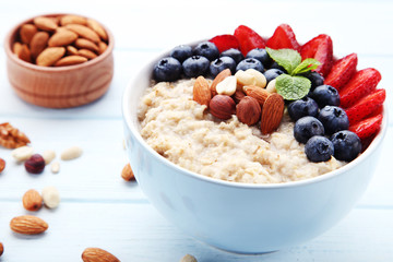 Oatmeal with berries and nuts in bowl on wooden table