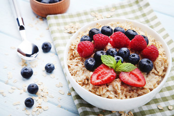 Oatmeal with berries in bowl on wooden table