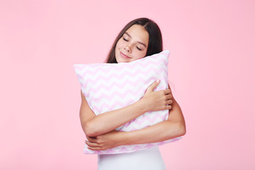 Young girl with pillow on pink background
