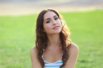 Portrait of young woman sitting on green grass in the park