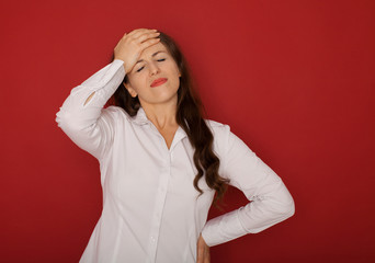 Fototapeta premium A businesswoman with a headache holding head, isolated on red background