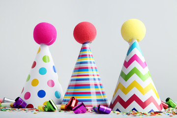 Birthday paper caps with blowers and confetti on grey background