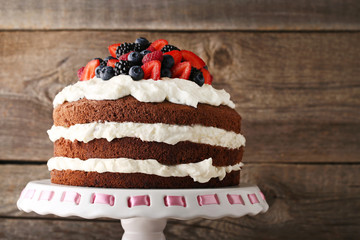 Delicious chocolate biscuit cake with berries on cake stand