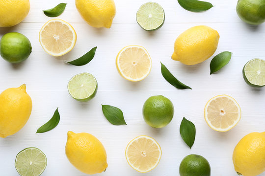Lemons and limes with green leafs on white wooden table
