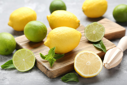 Lemons and limes with mint leafs on grey wooden table