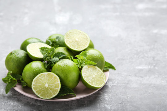 Ripe limes in plate on grey wooden table