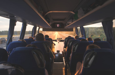 Bus with people going on the road in the evening at sunset. Photo interior of the bus. Background....