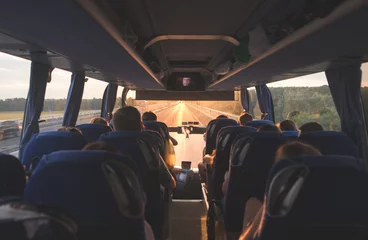 Fotobehang Bus with people going on the road in the evening at sunset. Photo interior of the bus. Background. Bus tourists © bodnarphoto
