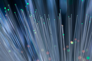 Glowing green and red optical fibres close up macro shot on dark blue background.