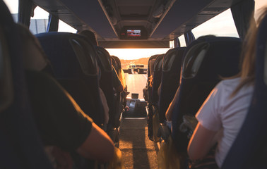 People ride in the bus at sunset. Salon bus with tourists. Selective focus of the bus interior with tourists at sunset.