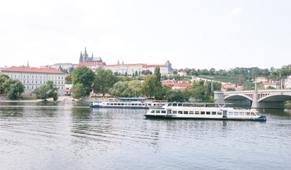 Panoramic photo of Prague, Czech Republic. Cruise ships float along the river Vltava, bridge and old architecture.