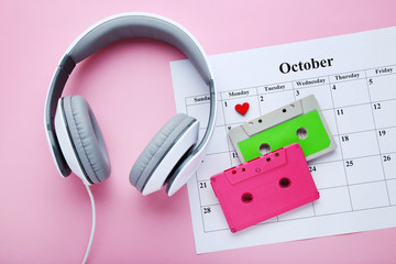 Headphones with cassette tapes and october calendar on pink background