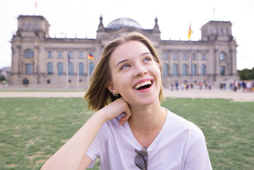 Portrait of a smiling girl in a white T-shirt against the backdrop of architecture in Berlin, Germany. Portrait of an attractive, happy tourist in Berlin on the background of the Reichstag