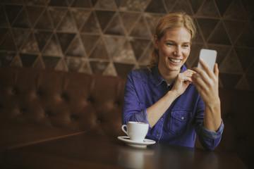 Pretty young woman with mobile phone in the cafe