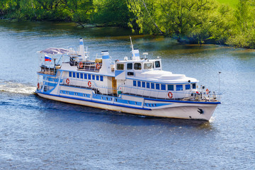 Aerial view on a small ship on the river a background of green trees on the shore