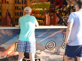 A man shoots a rifle in the prize dash, the view from the back, the amusement Park in the summer