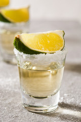 Mexican Gold tequila with lime and salt on gray background