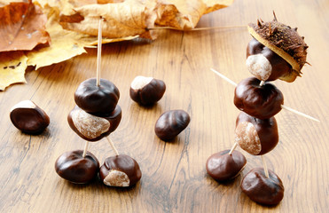 Creating Chestnut figures made of nuts. Maple leaves in background.