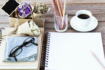 Flower bouquet with notebook the latte coffee cup and glasses on wooden table background.(with copy space for text)