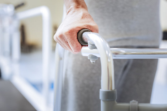 Disabled person. Aged paralyzed confident person being concentrated while trying to walk with a help of a special walking frame