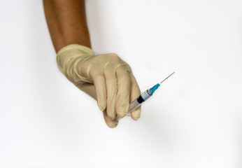 Hand in medical latex light yellow glove with syringe with drop of drug on needle isolated on white...