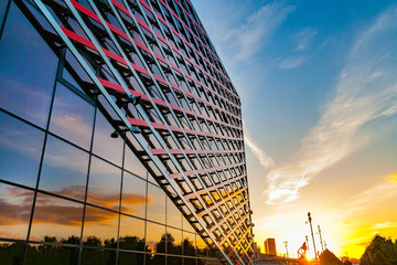 Perspective view of a fragment of the facade of a modern building of glass and iron on a sunset sky...