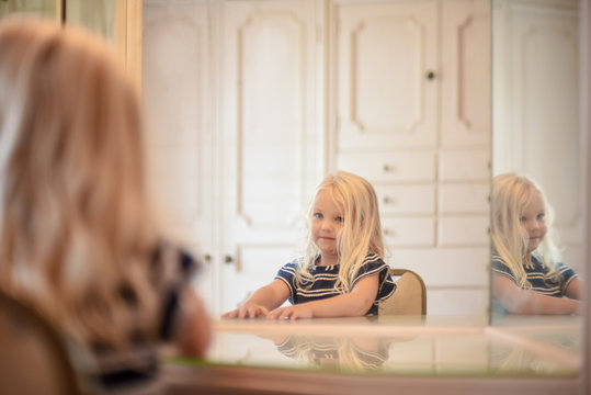 Little girl sitting at vanity mirror looking at her reflection