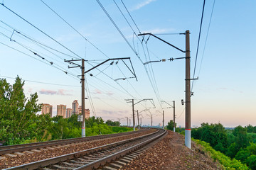 Fototapeta na wymiar Perspective view of a railroad with power line support a background of evening sky