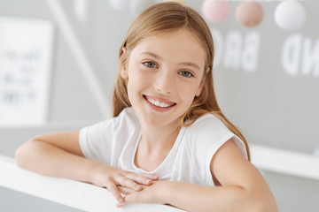 Waiting for you. Charming teenager holding hands together and keeping smile on face while posing on camera