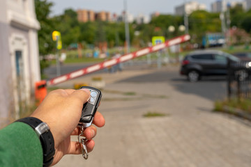 The remote system of the admission, male hand with the control panel opens a barrier for journey