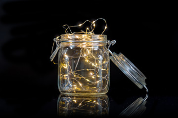 string lights in an open mason jar isolated on black background